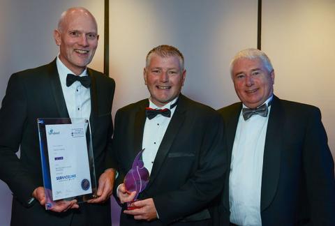 Three men on stage receiving award