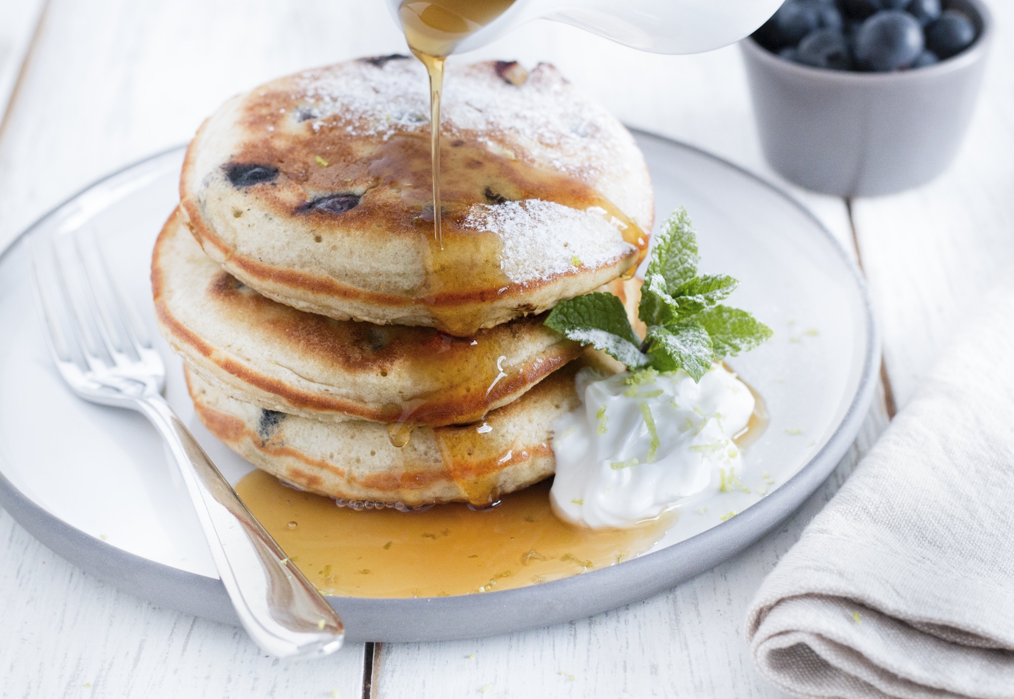 A stack of Blueberry and lime Scotch pancakes with maple syrup