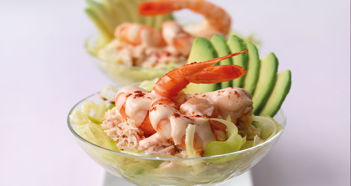 A bowl of avocado, prawn, and crab cocktail on fennel salad