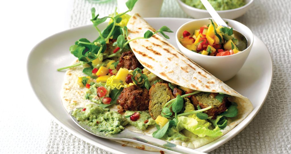 Falafel buritto on a plate with a side of salad