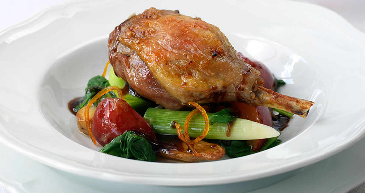 A plate of duck confit with vegetables