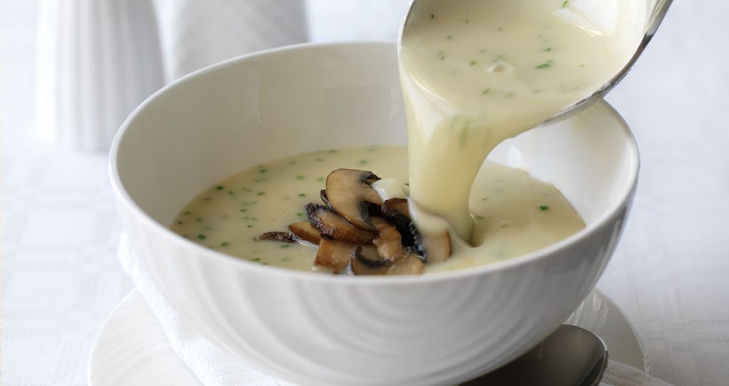 A bowl of creamy Celeriac and field mushroom soup with chive oil.