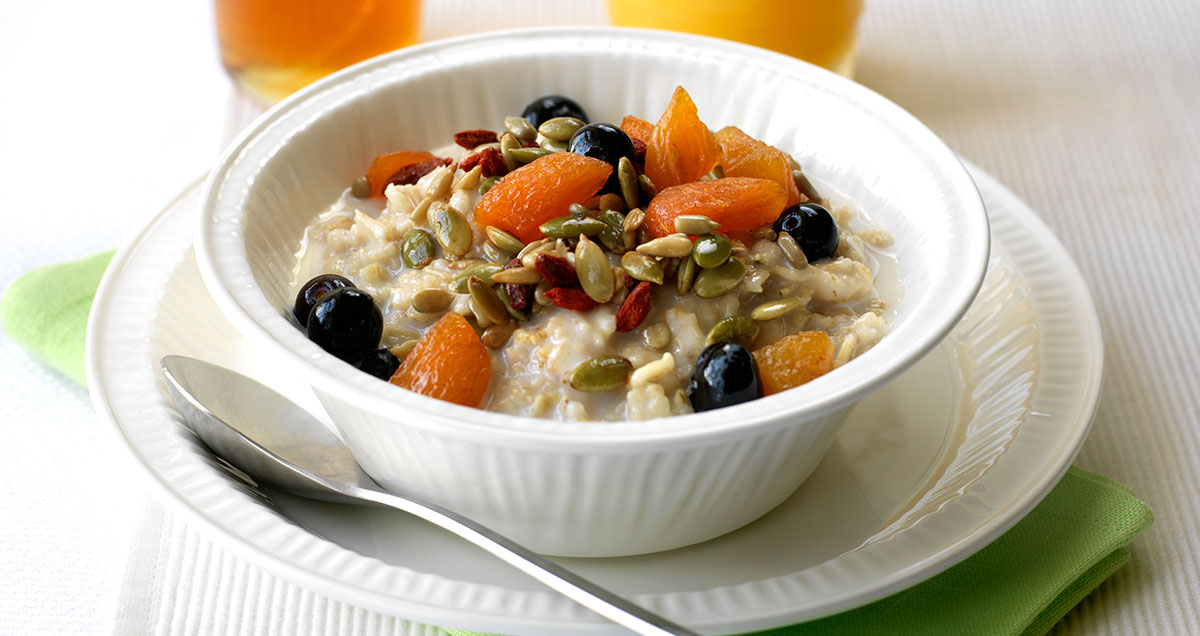 A bowl of porridge with fruit and seeds