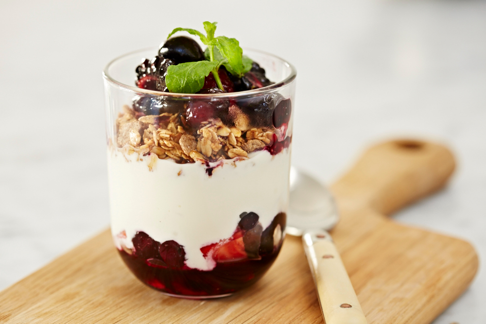 glass of yogurt parfait with granola and cherry jam