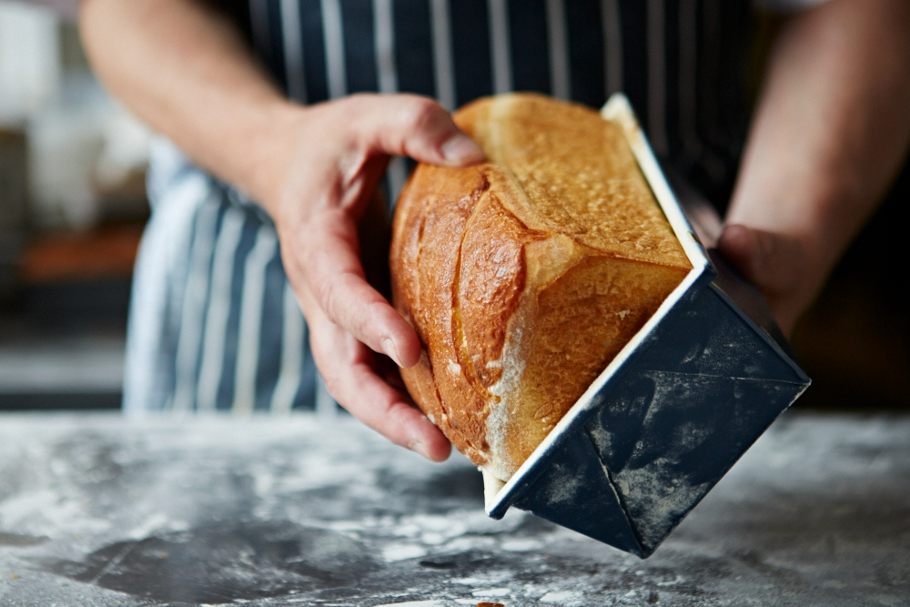 close-up of chef taking freshly bakes bread out of baking tray