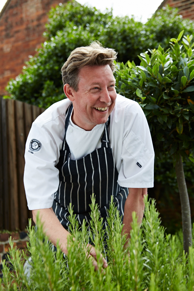 Man smiling while picking herbs in the garden