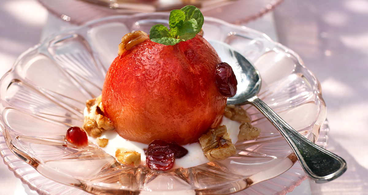 One roasted peach with walnuts and dried cranberry crème fraîche on a platter