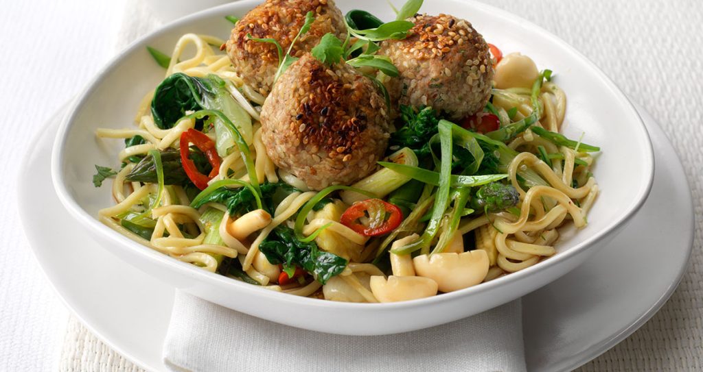 A bowl of sesame-coated turkey meatballs with noodles