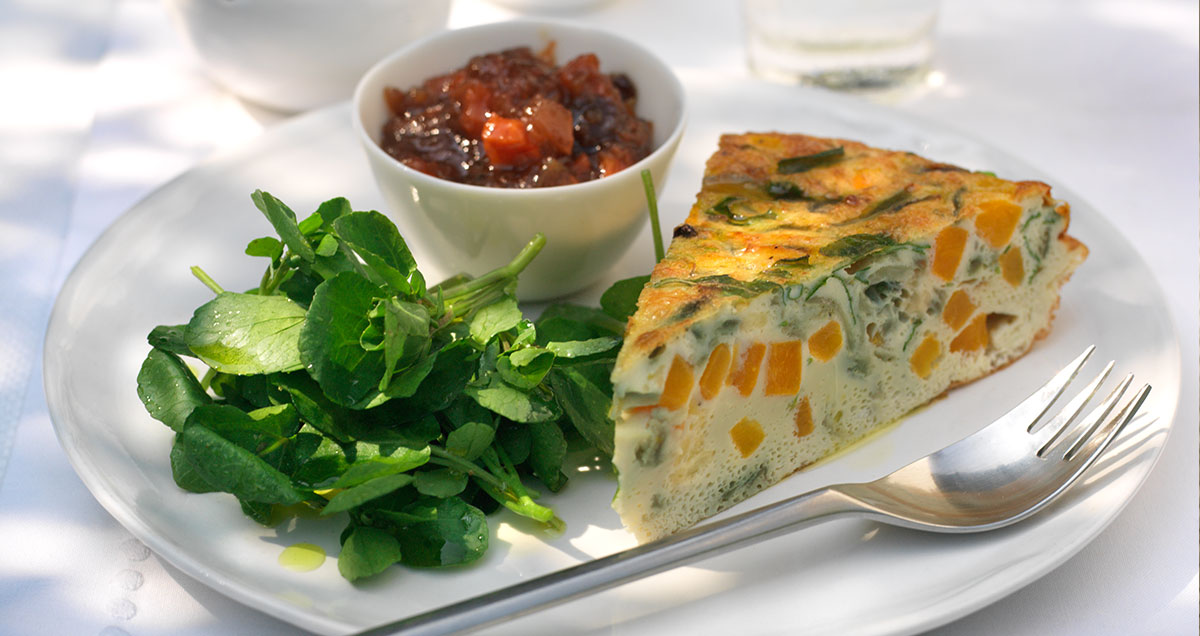 A slice of Roasted squash and herb frittata with watercress salad
