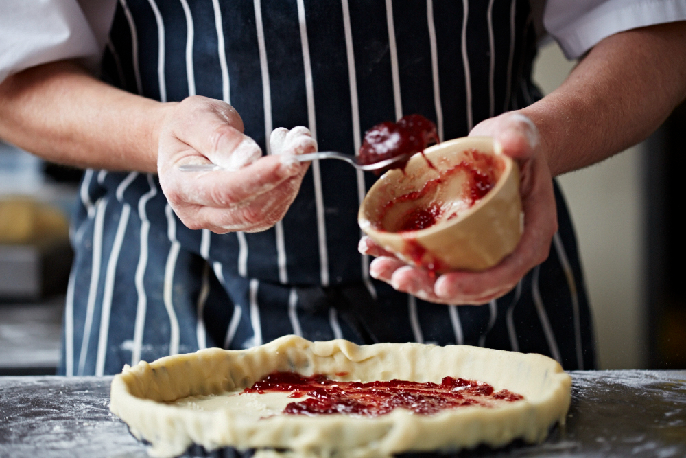 Close-up of chef spreading jam into pie pastry